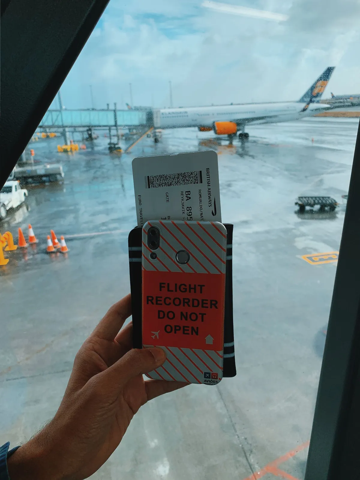 A traveler holding a phone and boarding pass at an airport