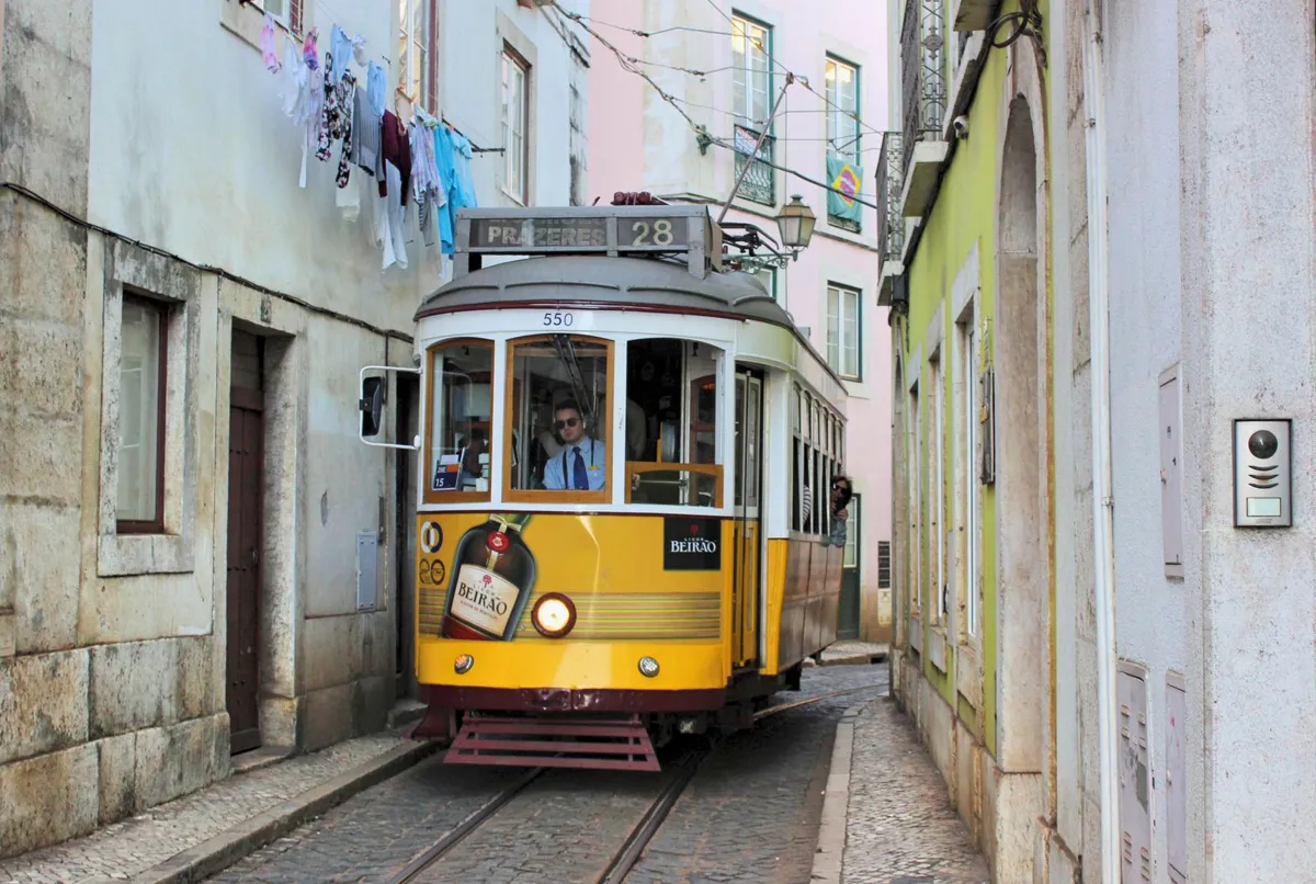 Yellow tram on a narrow street in Lisbon, Portugal